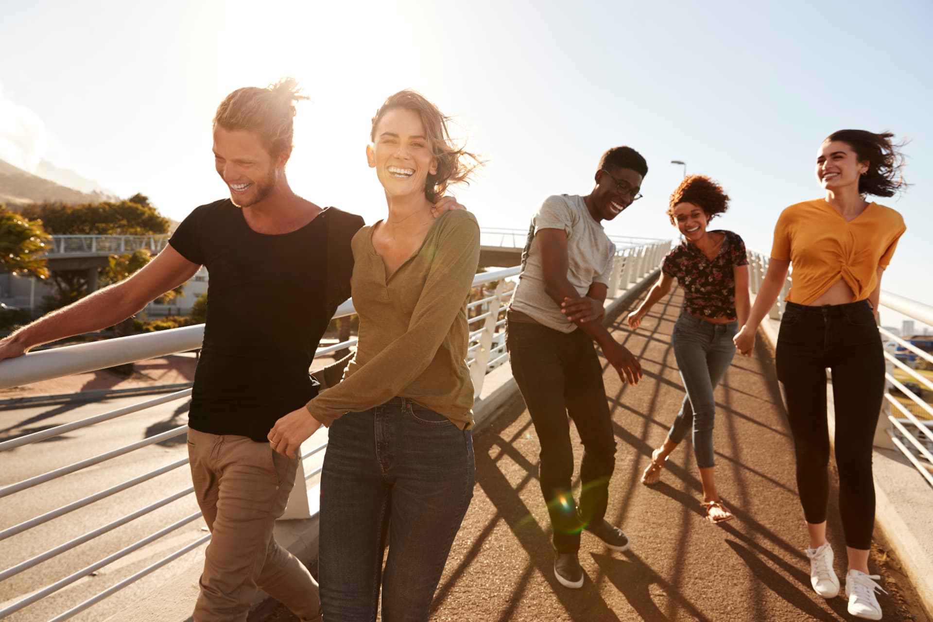 Five cheerful friends strolling together on a sunny bridge